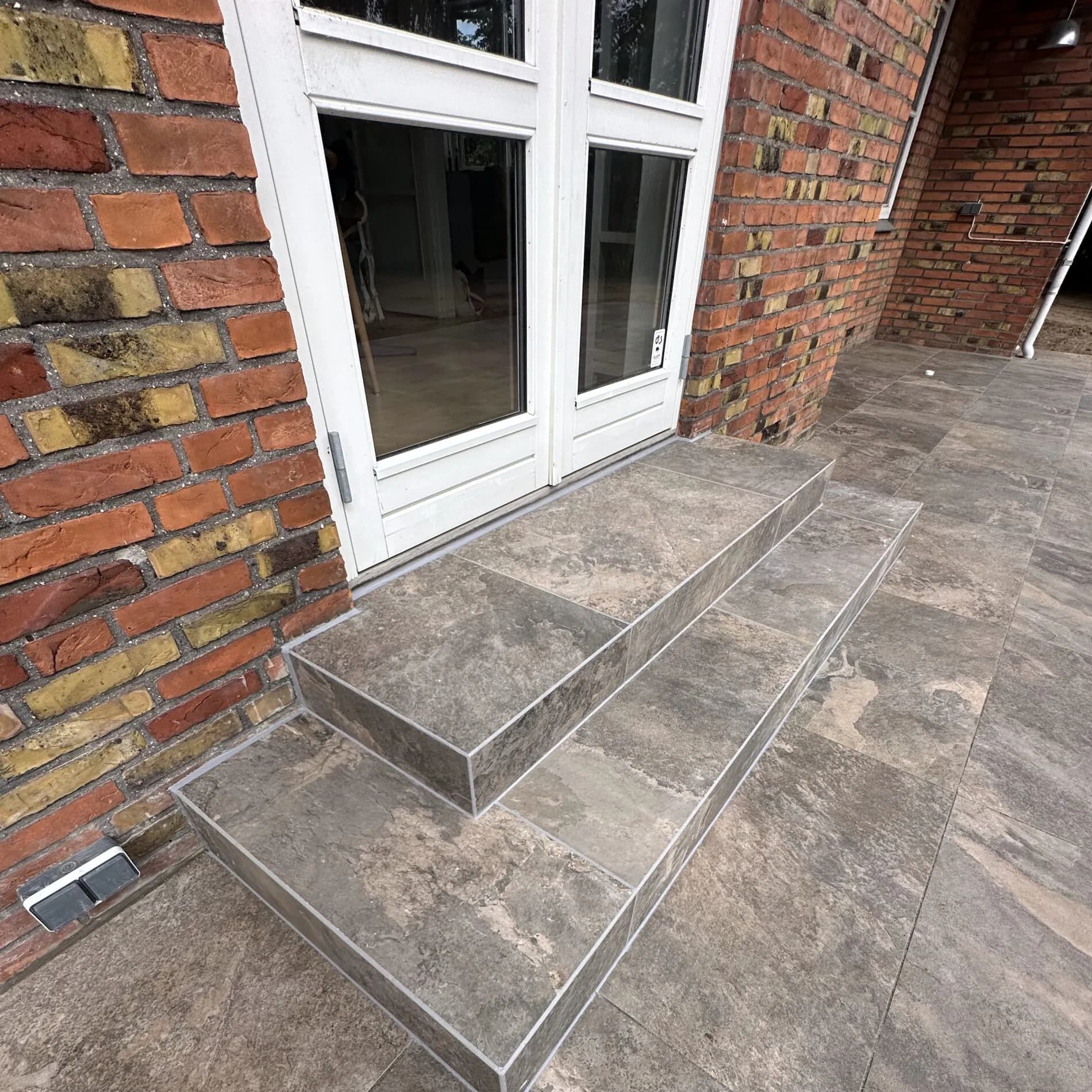 Flisetrappe - Keramiske frostsikre fliser lagt på trappe ved indgang. Skridsikker overflade og præcise fuger hele vejen.